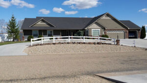 Large Idaho house with a pretty white fence in front of the half moon driveway